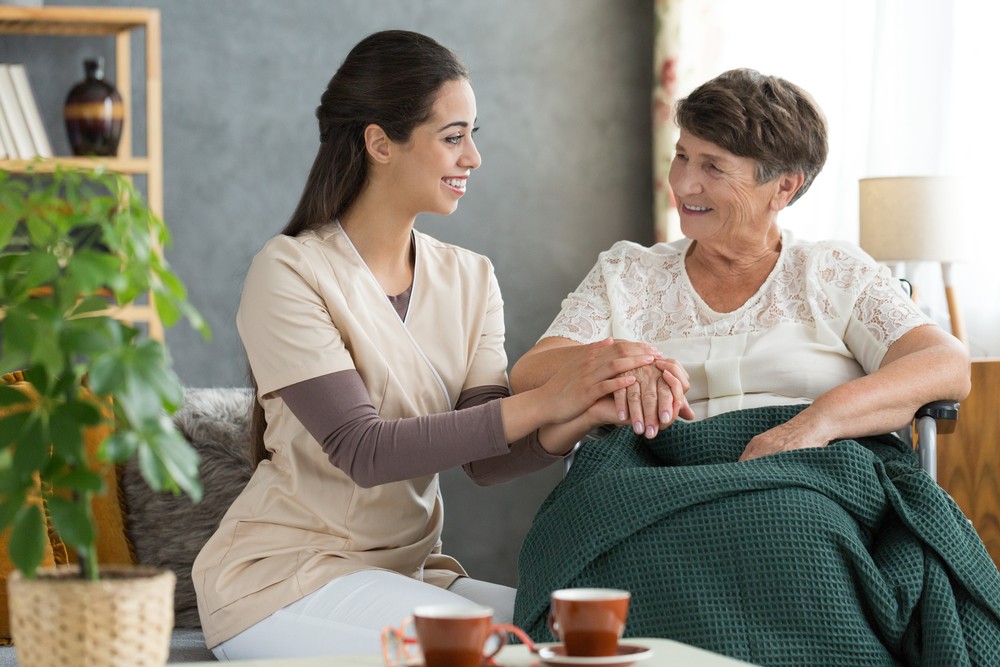 Senior woman sitting with caregiver in rehabilitation