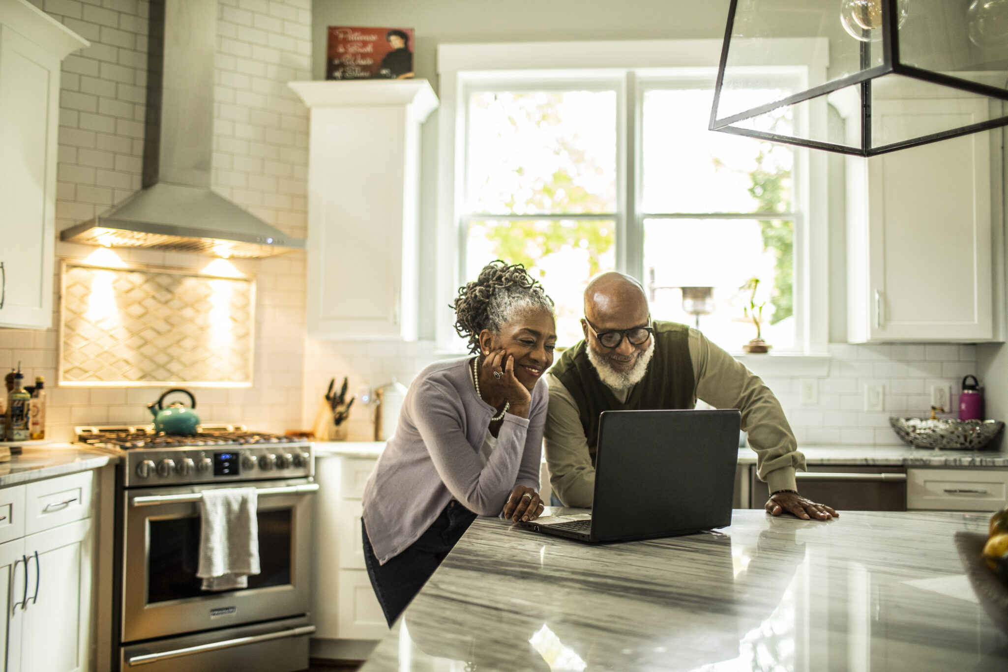 A senior couple in a modern kitchen looking at a computer together