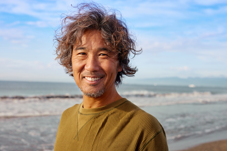 A senior man smiling for a photo at the beach