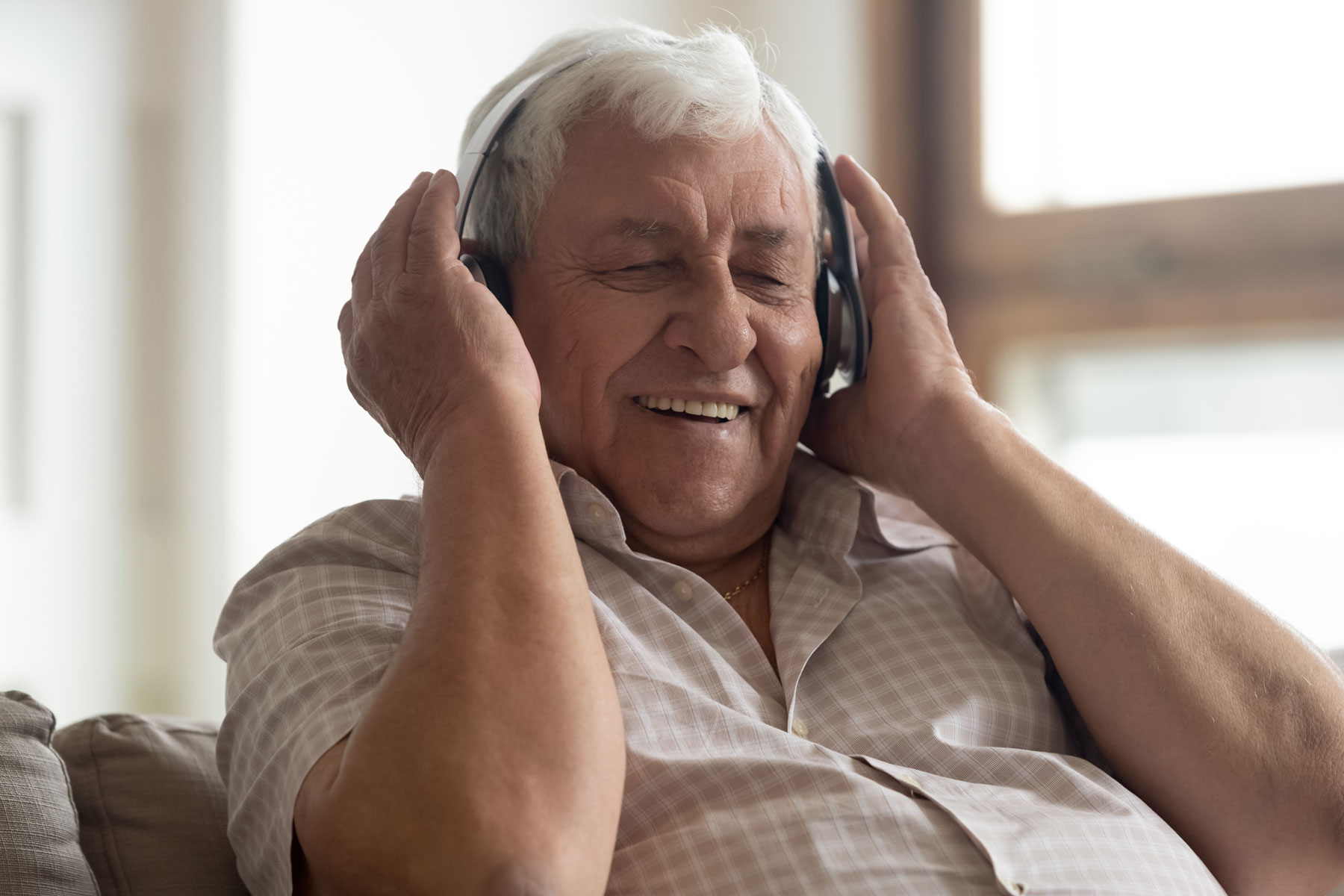 a senior male listens to music with headphones