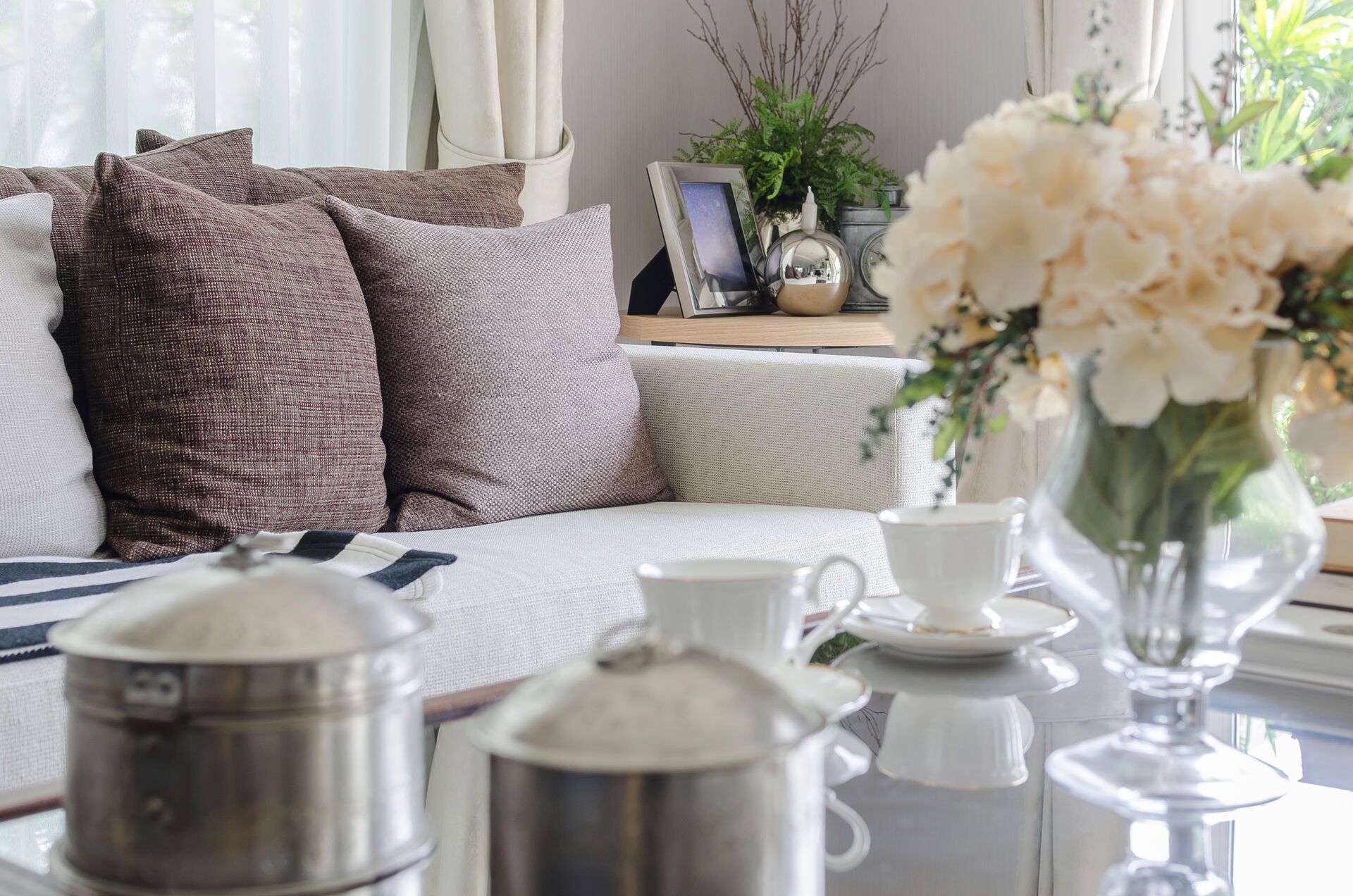 A light and airy living room with fresh flowers and china on the coffee table.